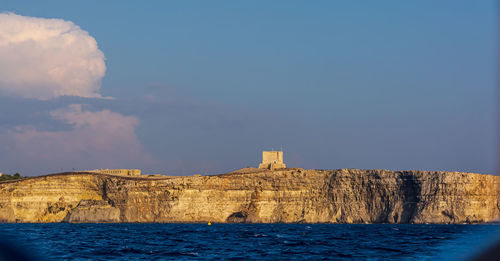 Built structure by sea against blue sky