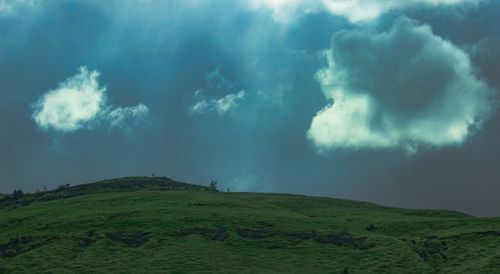 Scenic view of green landscape against cloudy sky