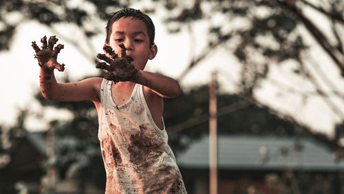 Portrait of boy holding camera while standing outdoors