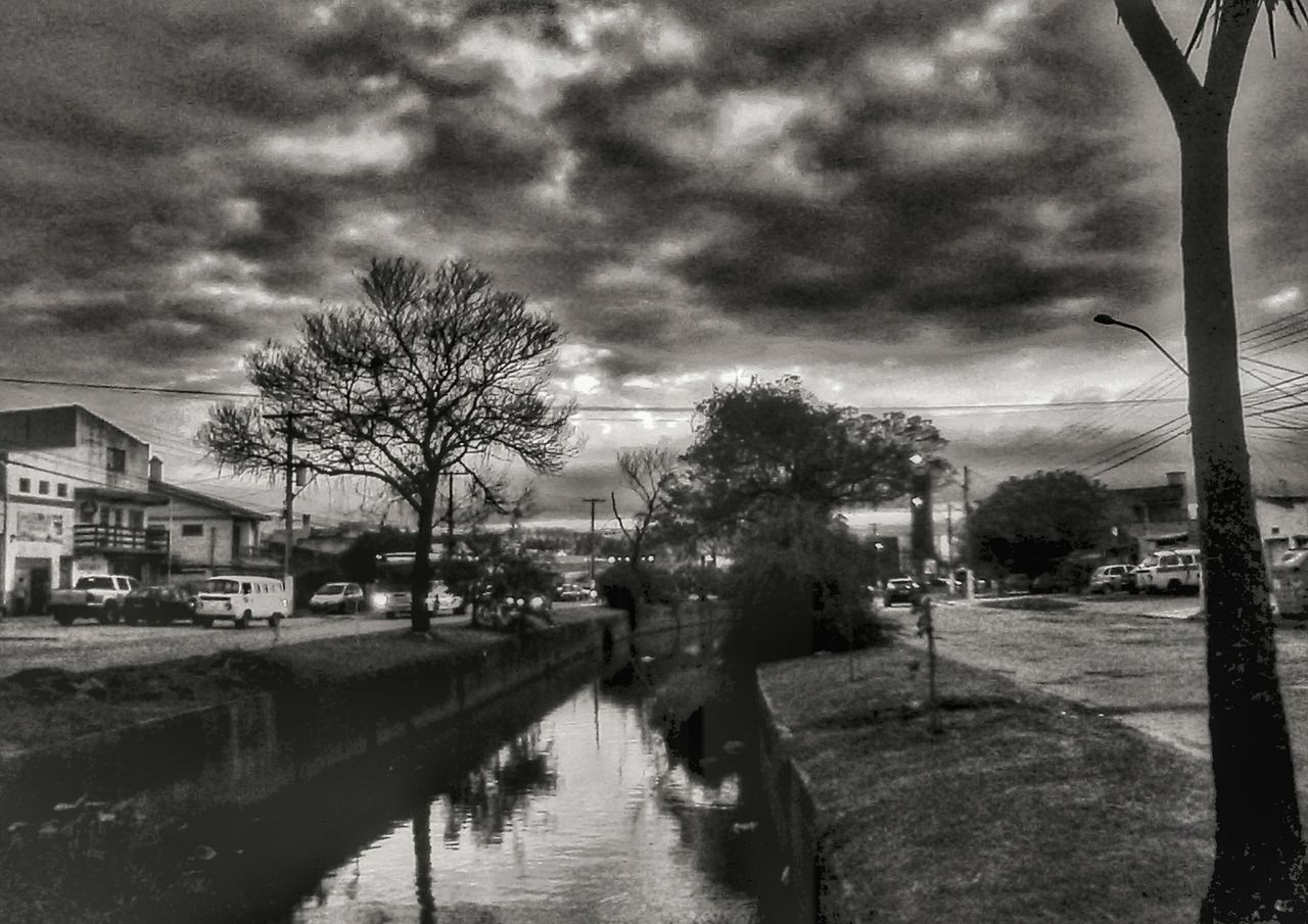 building exterior, water, sky, architecture, cloud - sky, built structure, tree, cloudy, canal, weather, city, transportation, reflection, street, cloud, overcast, waterfront, mode of transport