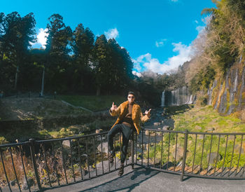 Full length of young man sitting on railing