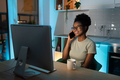 Remote female developer chatting on smartphone, enjoying flexible freelance schedule