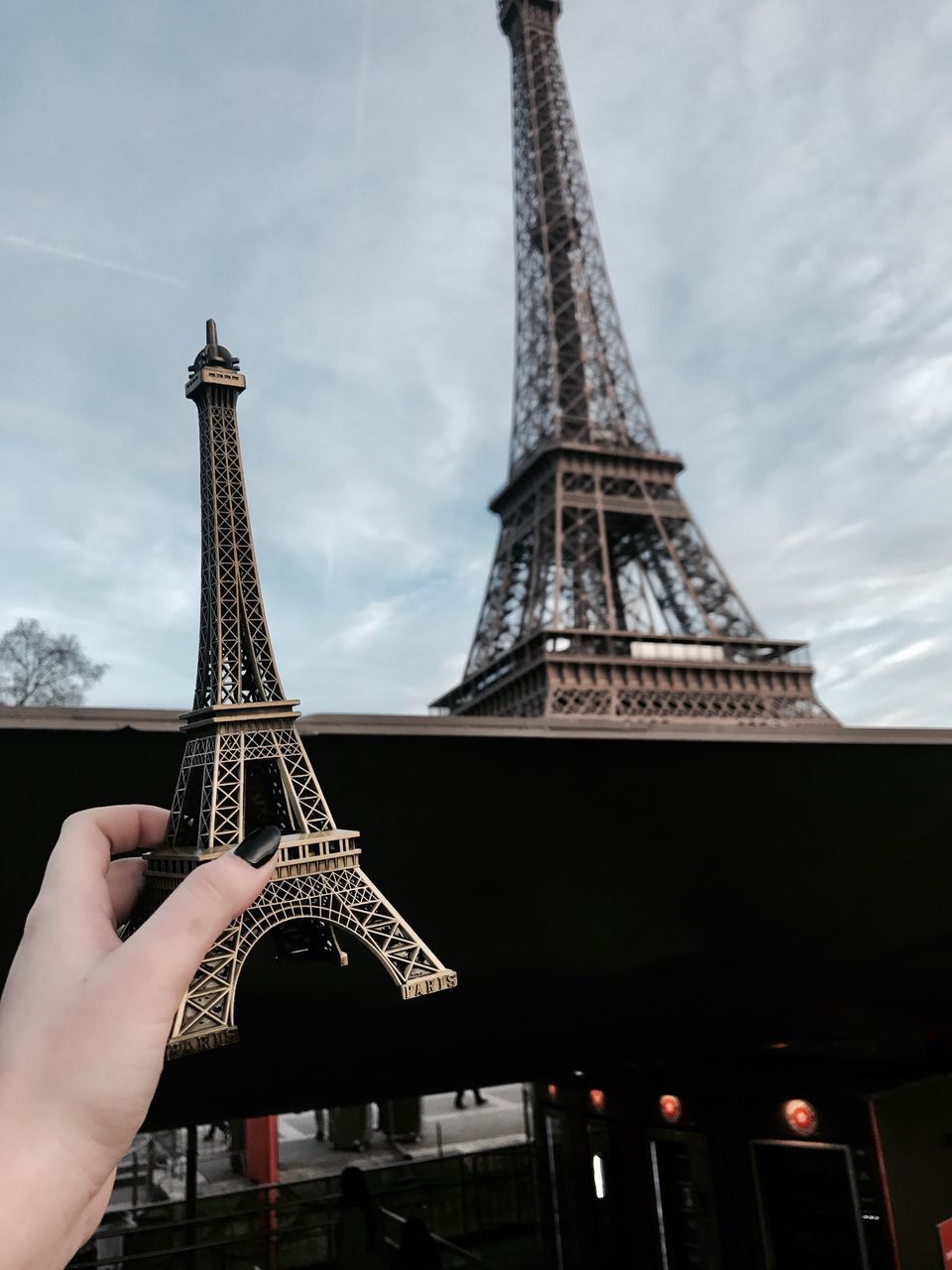 tower, built structure, architecture, tall - high, human hand, travel destinations, real people, tourism, history, unrecognizable person, human body part, holding, building exterior, outdoors, metal, one person, travel, low angle view, sky, day, leisure activity, city, tall, people