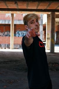 Portrait of young man standing against built structure