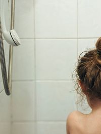 Rear view of shirtless woman in bathroom