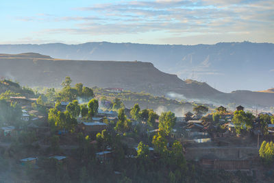 Scenic view of townscape by mountains against sky