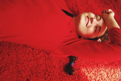 High angle view of smiling young woman lying on red rug