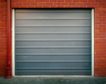 Grey corrugated garage door on red brick wall