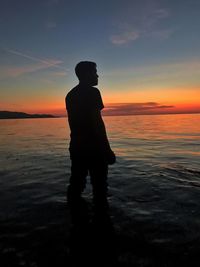 Silhouette man standing on beach against sky during sunset