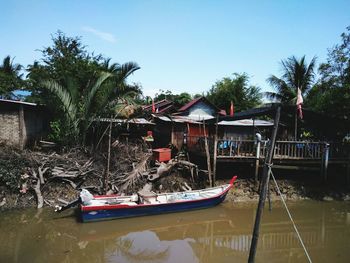 Boat moored in river by building against sky