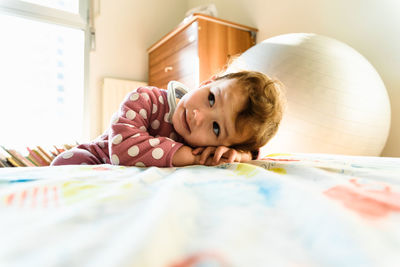 Portrait of cute baby lying on bed at home