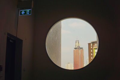 Buildings against sky seen through window