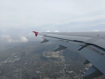 Aerial view of airplane wing over landscape against sky