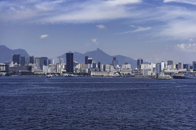 Sea by buildings against sky in city