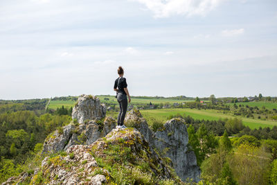 Woman standing on rock against sky