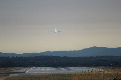 Airplane flying over runway against sky