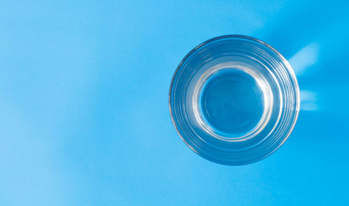 Directly above shot of water in drinking glass over blue background