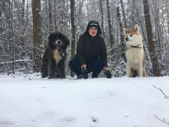 Portrait of man with dog sitting on snow