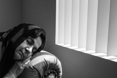 Close-up of woman relaxing by window at home