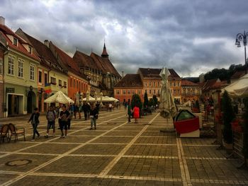 People in city against cloudy sky