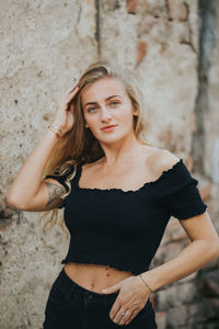 Portrait of beautiful young woman standing against wall