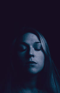 Close-up of young woman against black background