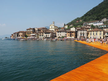 View of buildings by sea against sky in city