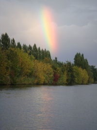 Scenic view of rainbow over lake against sky