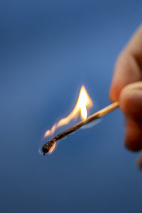 Close-up of hand holding burning matchstick 