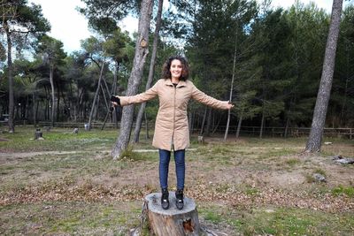 Portrait of smiling woman standing against trees