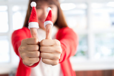 Close-up of woman with small santa hats on thumbs