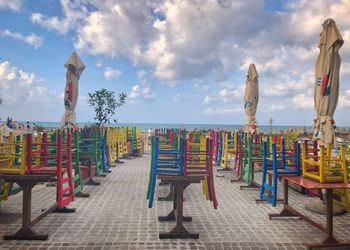 Multi colored chairs on beach against sky