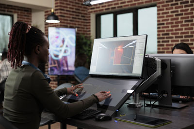 Rear view of woman using laptop at office