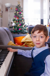 Portrait of boy sitting playing piano at home in christmas