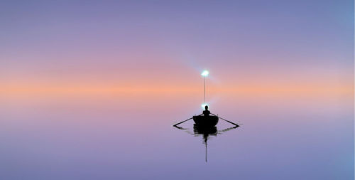 Silhouette person by sea against sky during sunset