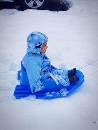 Boy tobogganing on snow covered field