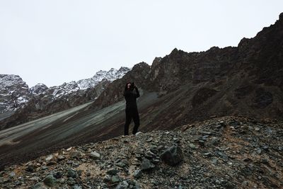 Full length of man standing on rock against sky