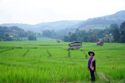 Portrait of smiling woman standing on rice paddy against sky