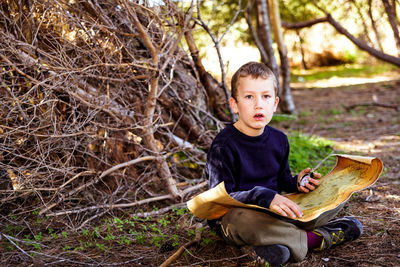 Portrait of boy sitting on tree