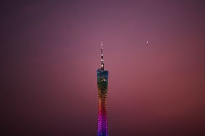 Communications tower in city against romantic sky