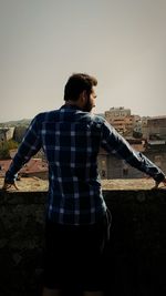 Rear view of man standing against clear sky