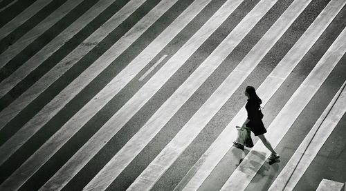 High angle view of woman walking on zebra crossing