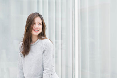 Smiling young woman against curtain at home
