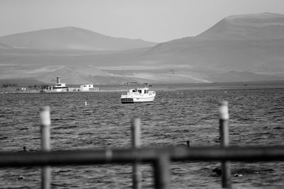 Boats sailing on lake against mountains