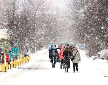 People walking on road during snowfall