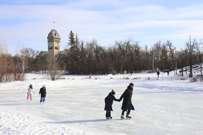 People on snow covered landscape against sky