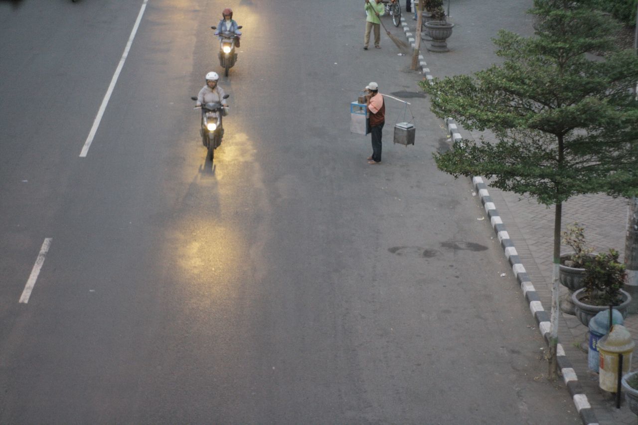 HIGH ANGLE VIEW OF PEOPLE WALKING ON ROAD ALONG TREES