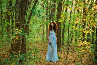 Person standing by tree trunk in forest