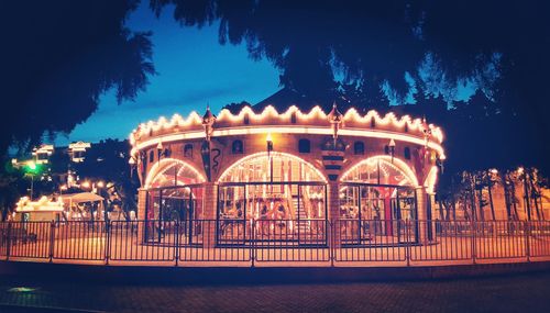 Illuminated amusement park against sky at night