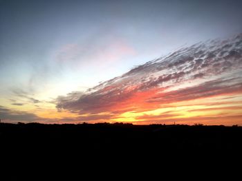 Silhouette landscape against dramatic sky during sunset